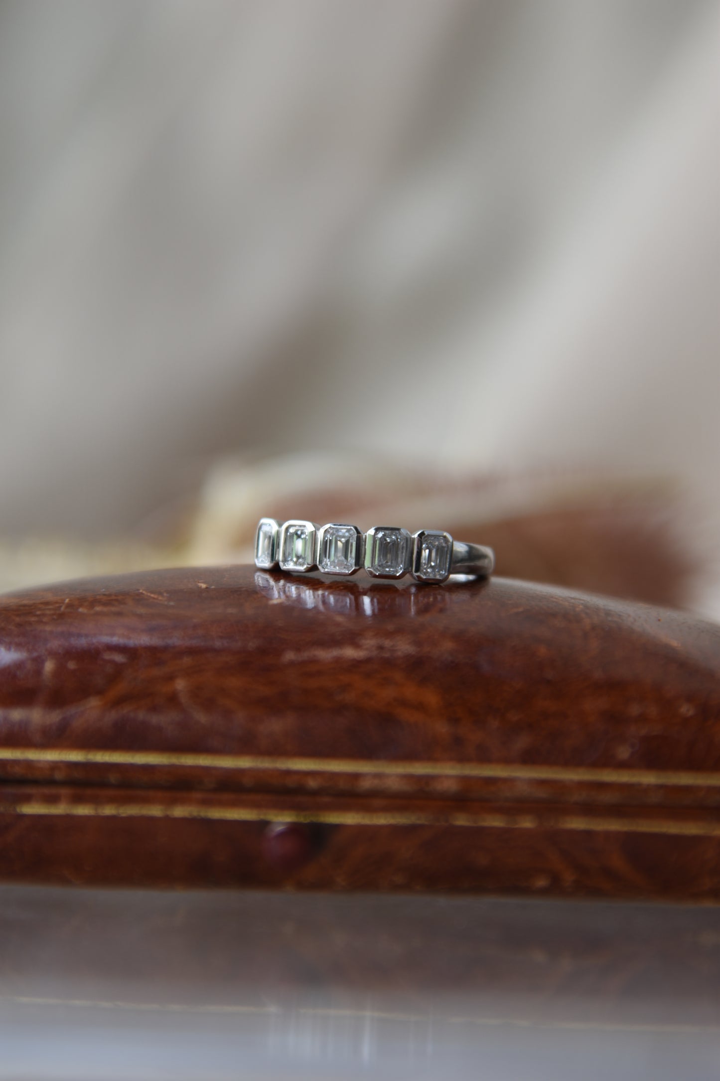 Anillo medio cintillo, oro blanco con baño de rodio y diamantes talla esmeralda