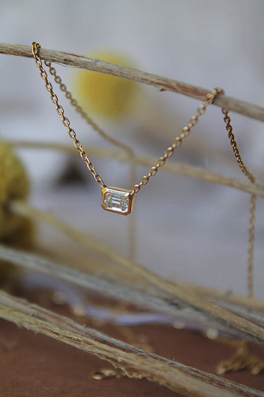 Collar modelo punto de luz, metal amarillo y diamante talla esmeralda.