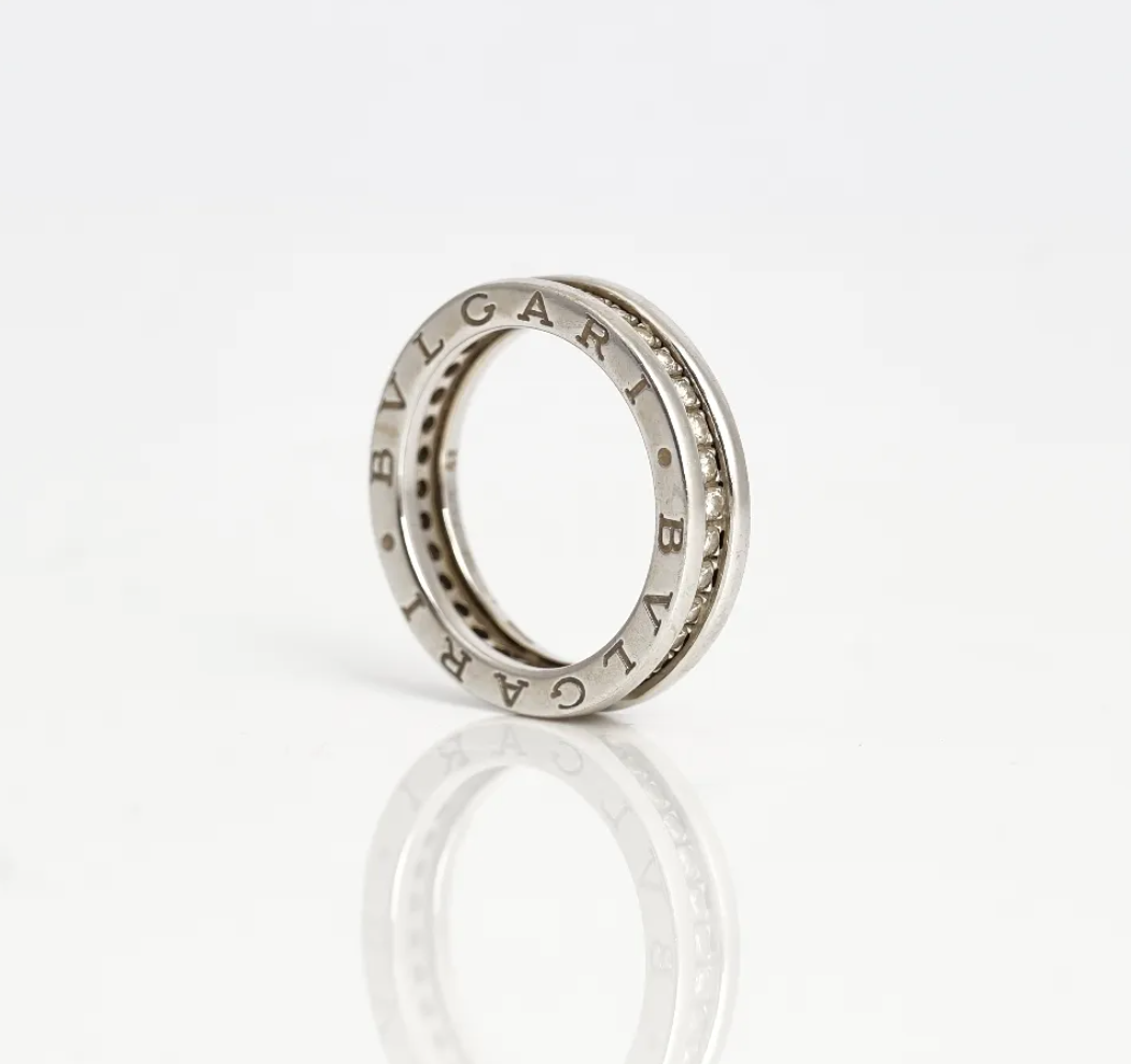 Anillo eternity, montado de diamantes por completo y oro blanco. Marca Bvlgari. En sus lados presenta dos detalles de grabado "Bvlgari".