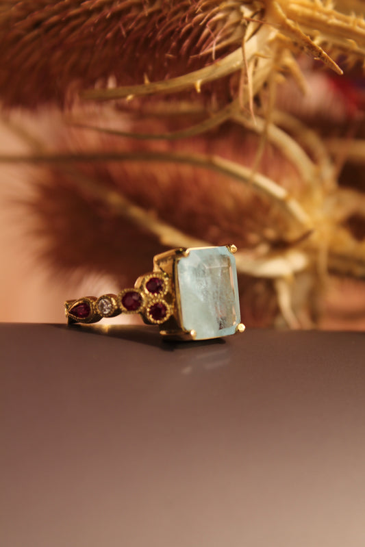 Anillo hecho a mano, mental oro amarillo, Aguamarina central, brillantes y rubíes.